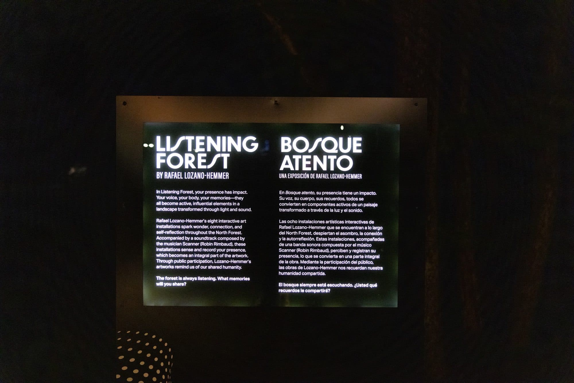 A lit kiosk label with the headline "Listening Forest, Bosque Atento."
